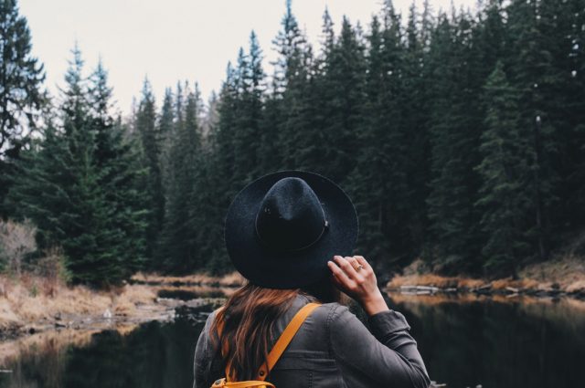 Girl with hat in the woods carrying a yellow backpack